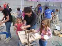 Kinder und Steinmetze arbeiten am Naturstein