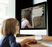 Ein Mädchen schaut auf einen großen Computerbildschirm, der eine Seite von DENKMAL EUROPA zeigt